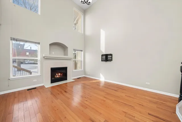 a view of an empty room with wooden floor fireplace and a window