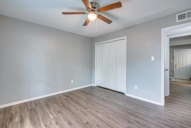 an empty room with wooden floor and windows