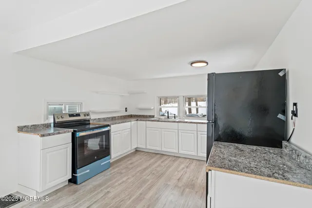a kitchen with granite countertop a sink stove and refrigerator
