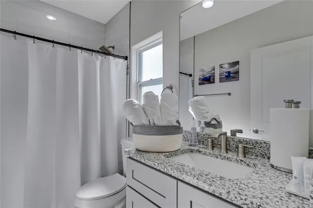 a bathroom with a granite countertop sink and a toilet