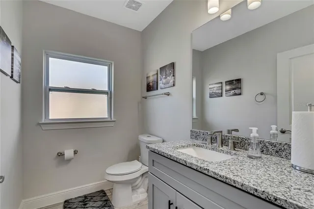 a bathroom with a granite countertop sink a toilet and a mirror