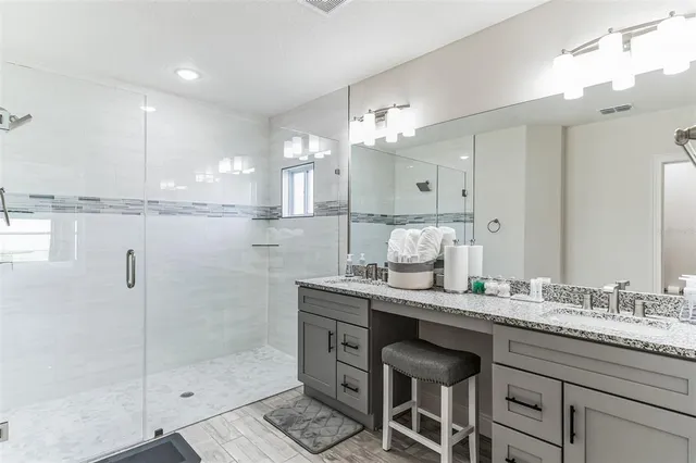 a bathroom with a granite countertop sink a mirror and a shower