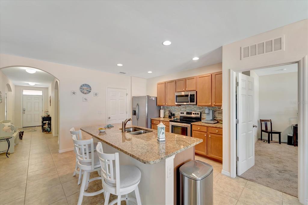 8997 Excelsior Loop Venice, FL 34293 - Photo 21 of 48 a kitchen with stainless steel appliances granite countertop a stove top oven a sink a refrigerator and a dining table with white countertops