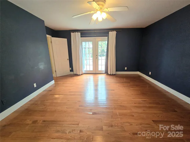 a view of an empty room with window and wooden floor