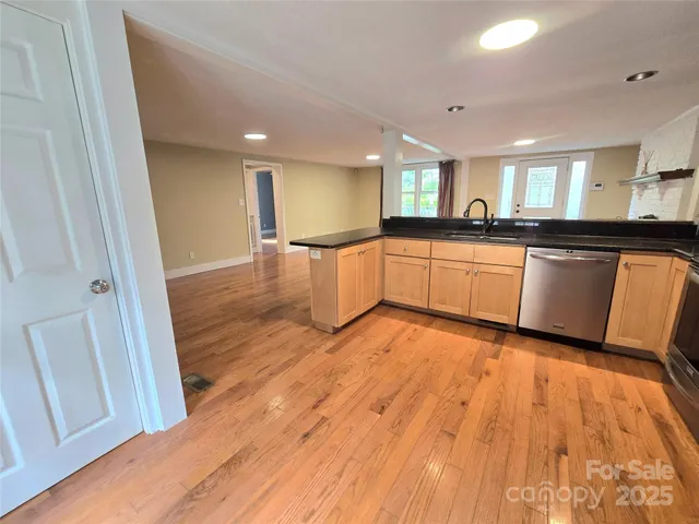 a large kitchen with a sink and wooden floor