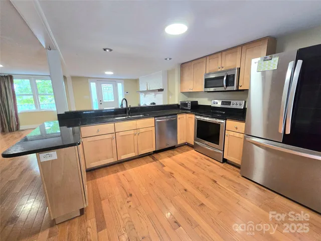 a large kitchen with stainless steel appliances granite countertop a stove a sink dishwasher and a refrigerator