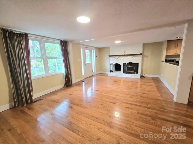 a view of an empty room with a window and wooden floor