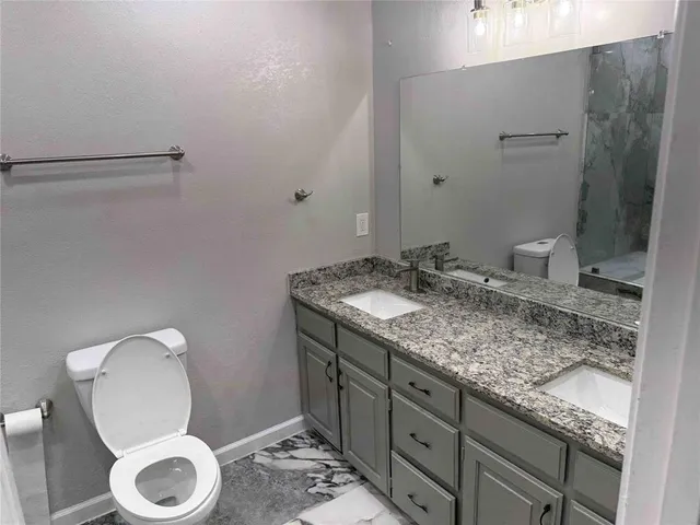 a bathroom with a granite countertop sink toilet and a mirror