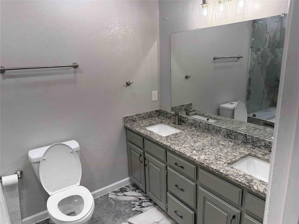 2959 Scott Mill Road Carrollton, TX 75007 - Photo 22 of 26 a bathroom with a granite countertop sink toilet and a mirror