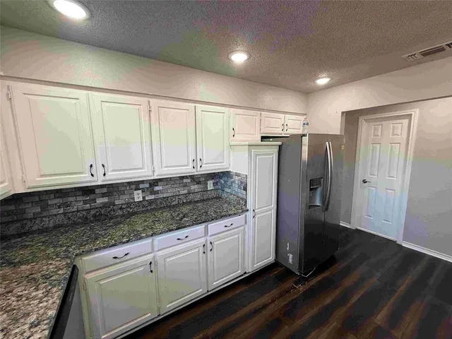 a kitchen with granite countertop a refrigerator and a sink