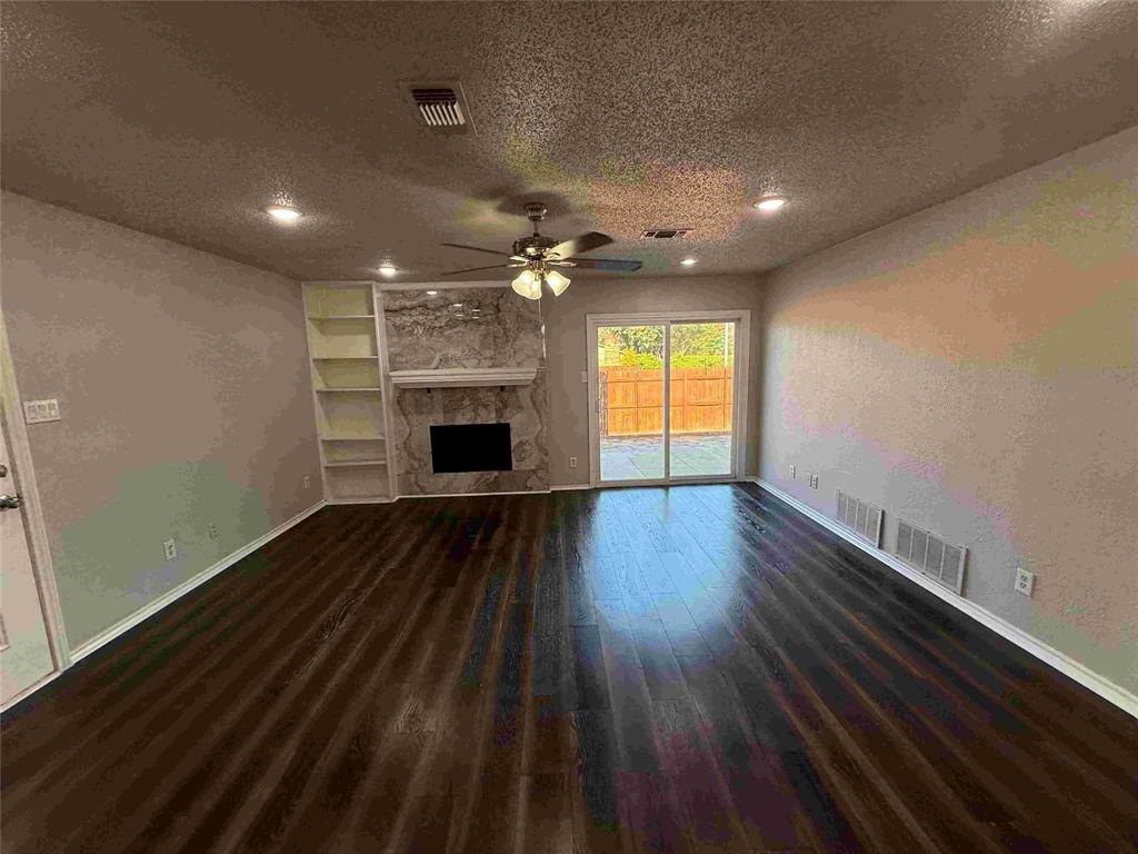 2959 Scott Mill Road Carrollton, TX 75007 - Photo 8 of 26 an empty room with wooden floor fireplace and windows