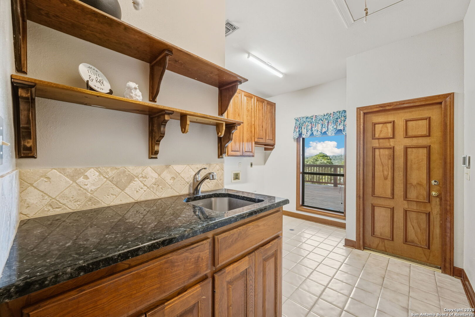 14819 Seven L Trail Helotes, TX 78023 - Photo 18 of 61 a kitchen with granite countertop a sink and a refrigerator
