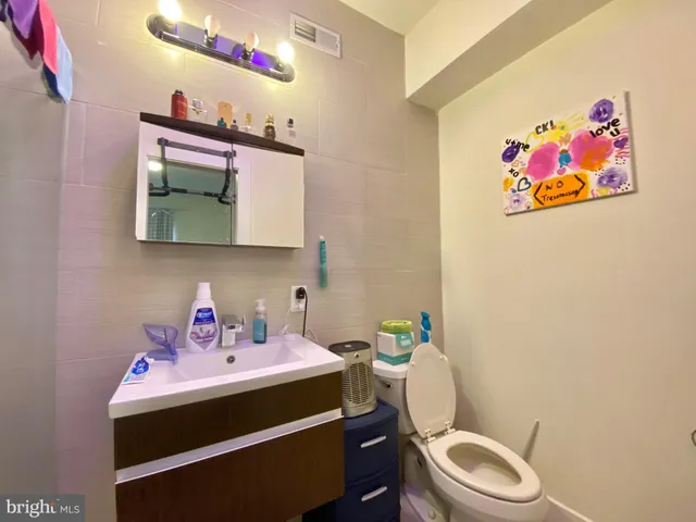 a bathroom with a toilet a sink and wooden floor