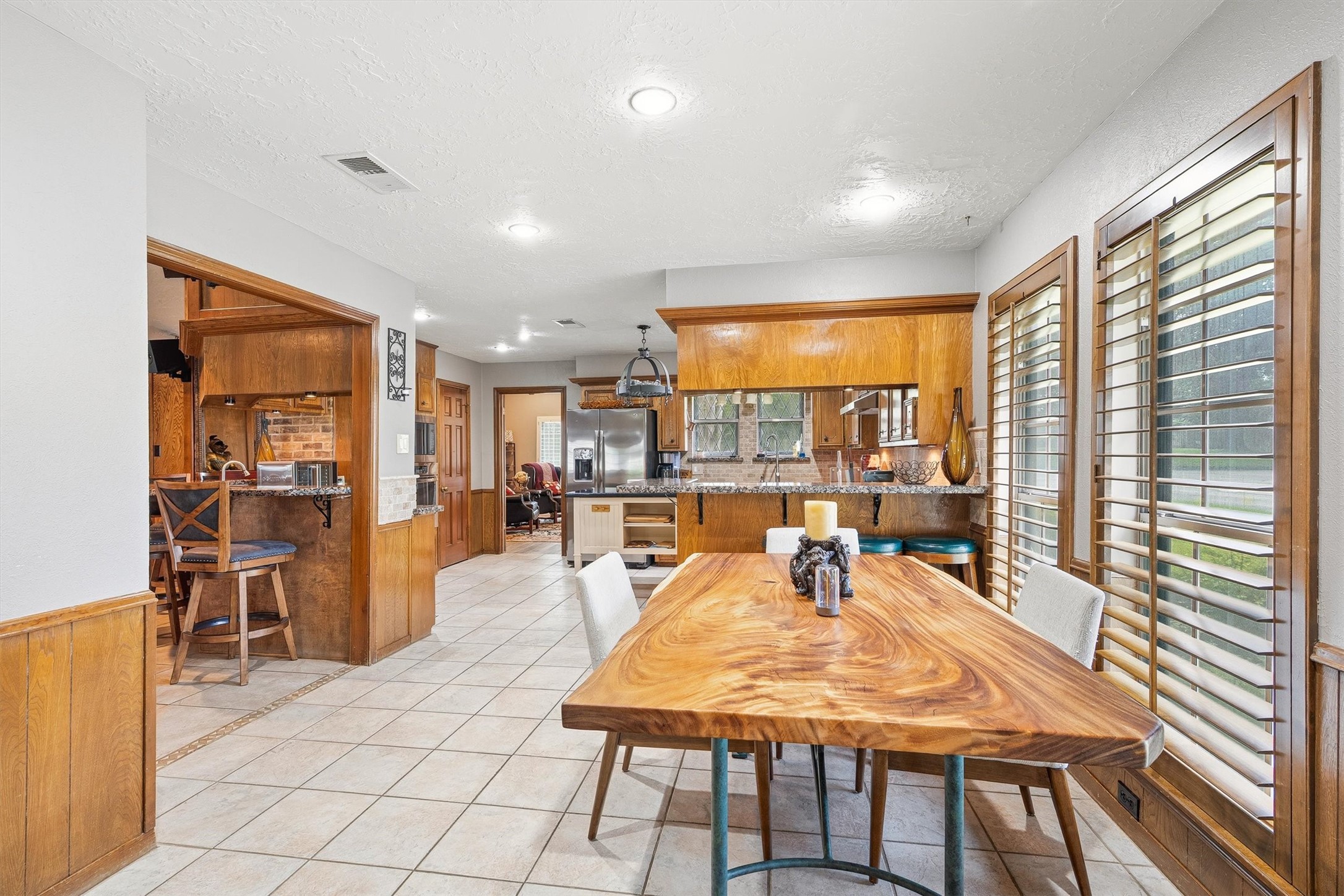 826 North Rivershire Drive Conroe, TX 77304 - Photo 18 of 46 This is what gathering looks like in this home. The dining area flows naturally into the kitchen, the wet bar, and the living room beyond, with backyard light coming through the wood shutters on the right. There is not a bad seat in the house.