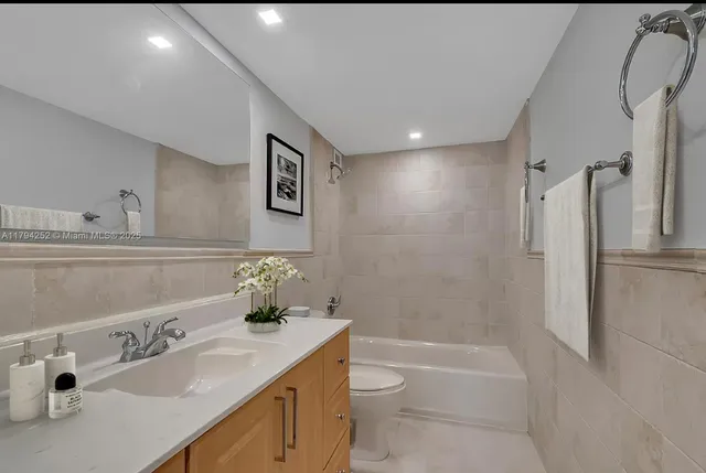a bathroom with a granite countertop sink a toilet and shower