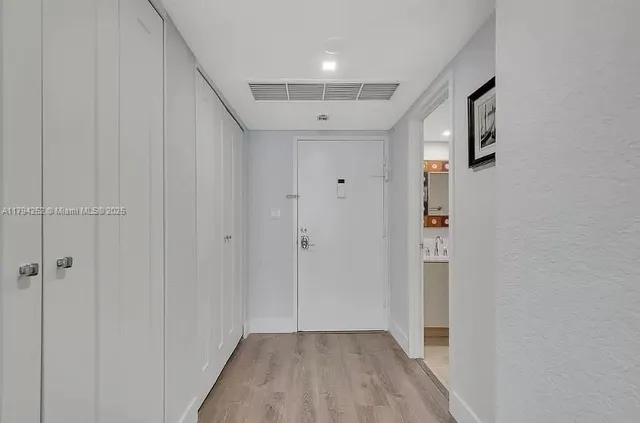 a view of a hallway with wooden floor and closet area