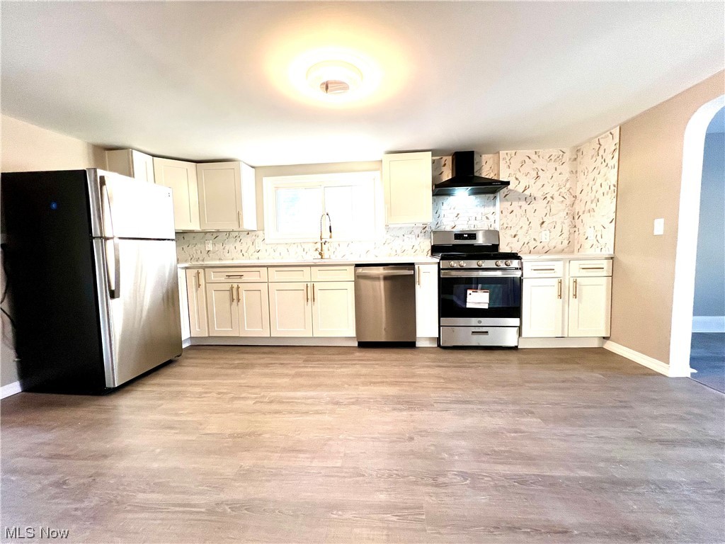 3527 Broadview Road Cleveland, OH 44109 - Photo 7 of 29 Kitchen with light hardwood / wood-style flooring, backsplash, sink, appliances with stainless steel finishes, and wall chimney exhaust hood