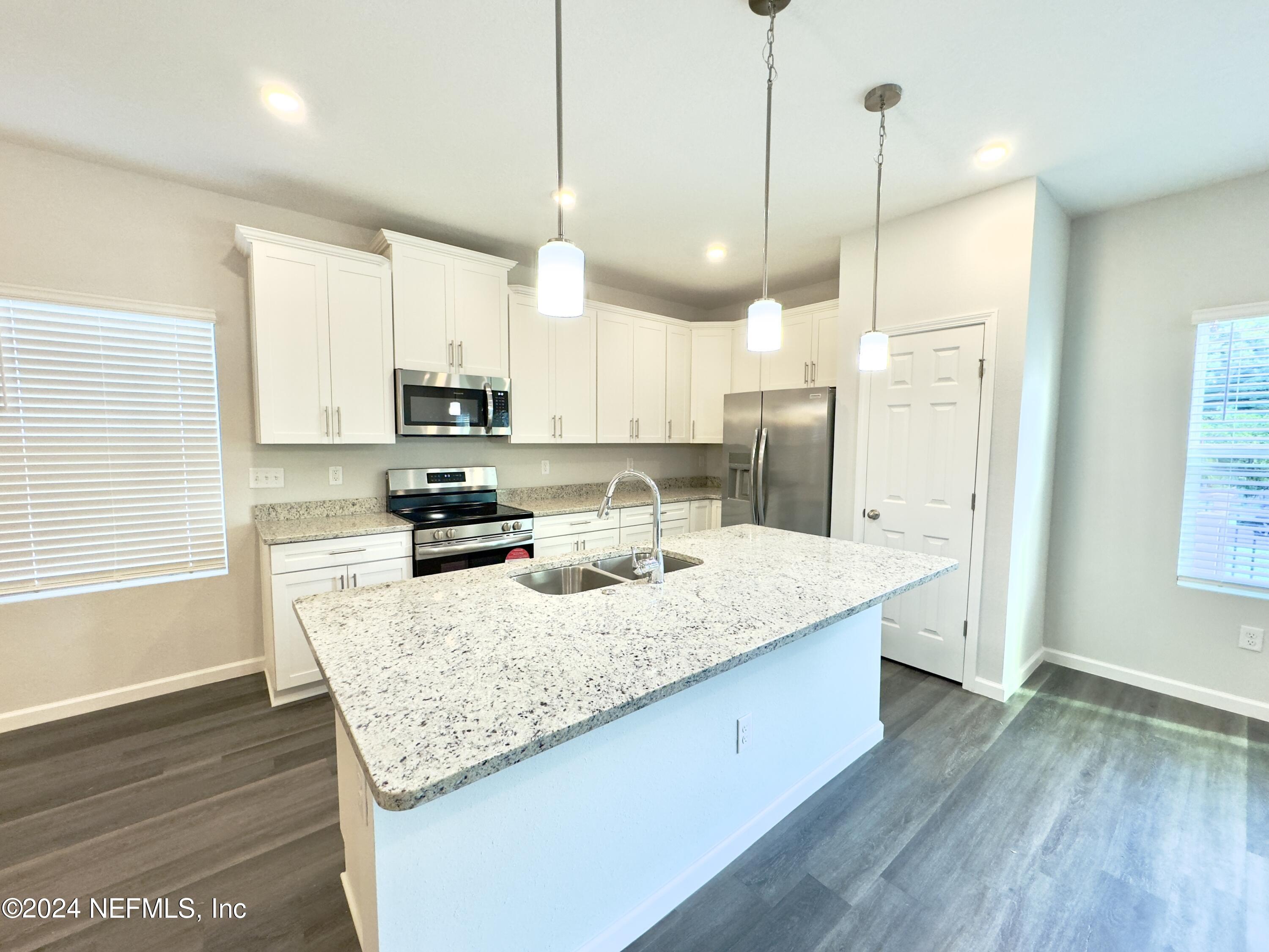 4672 Ribault Park Street Jacksonville, FL 32233 - Photo 6 of 22 a kitchen with stainless steel appliances granite countertop a sink a stove and a wooden floors