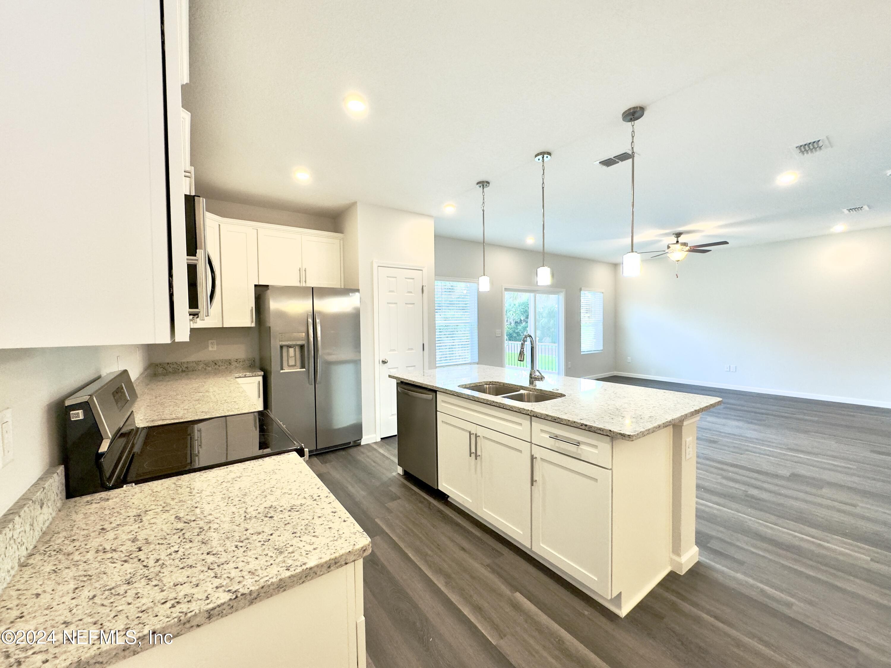 4672 Ribault Park Street Jacksonville, FL 32233 - Photo 7 of 22 a kitchen with a stove a sink a refrigerator and wooden floor