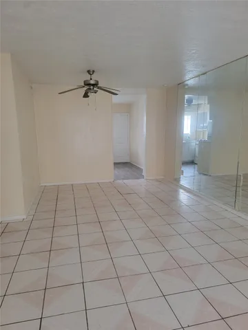 a view of an empty room and chandelier fan