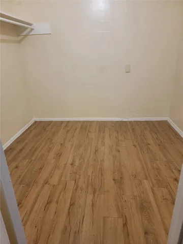 a view of a room with wooden floor and bench in it