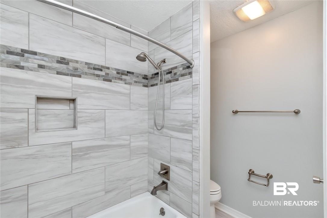6109 Timberly Road North Mobile, AL 36609 - Photo 18 of 26 Bathroom featuring a textured ceiling, tiled shower / bath, and toilet