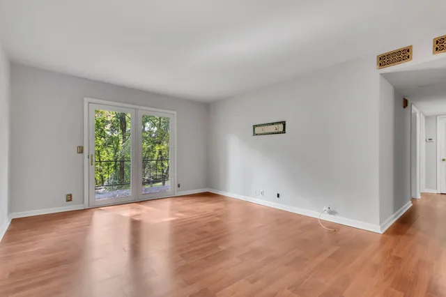 an empty room with wooden floor and windows