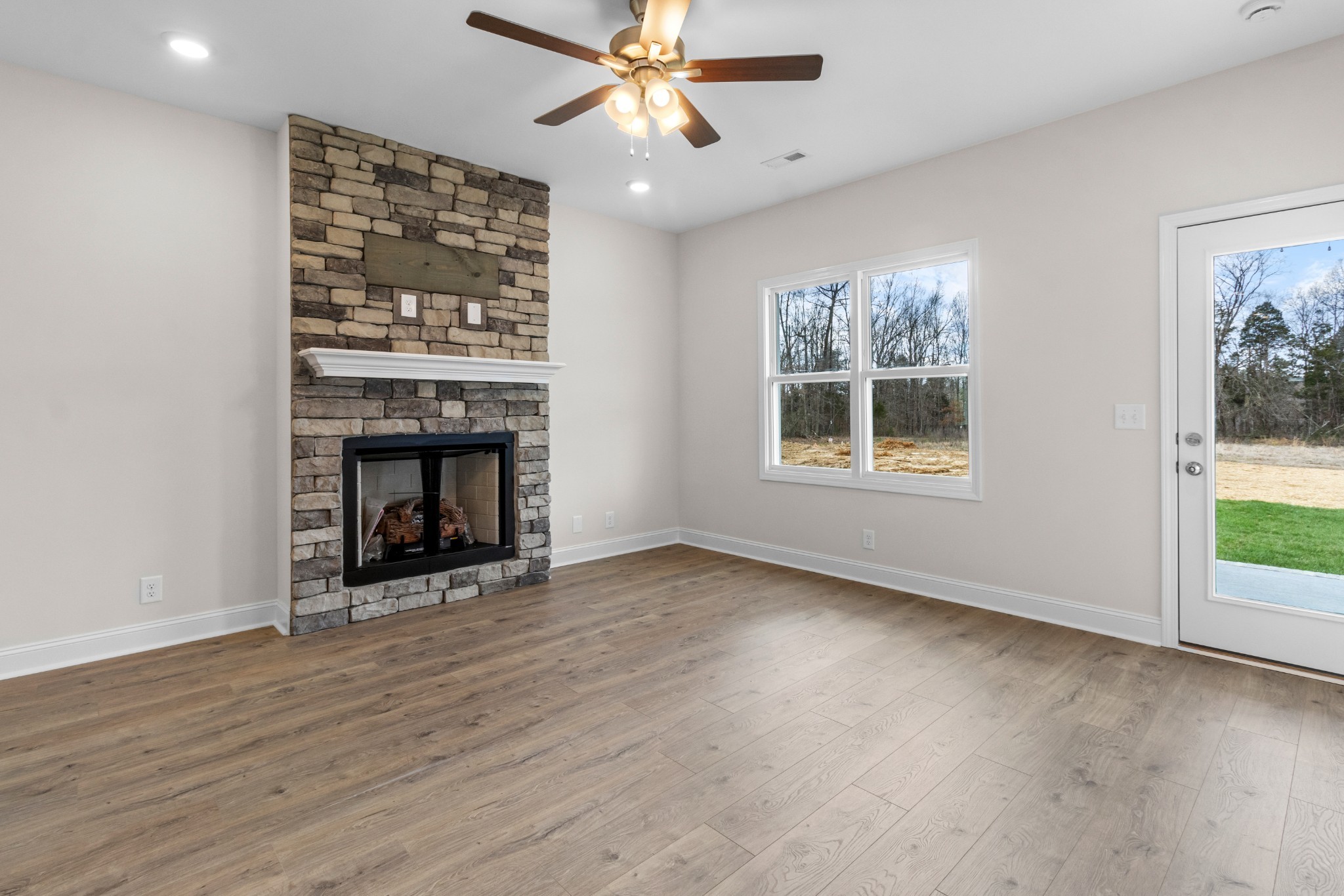 2138 Ireland Way Clarksville, TN 37042 - Photo 16 of 37 an empty room with windows a fireplace a ceiling fan and wooden floor