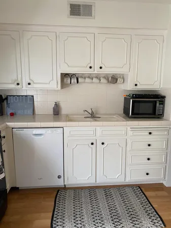 a kitchen with white cabinets and white appliances