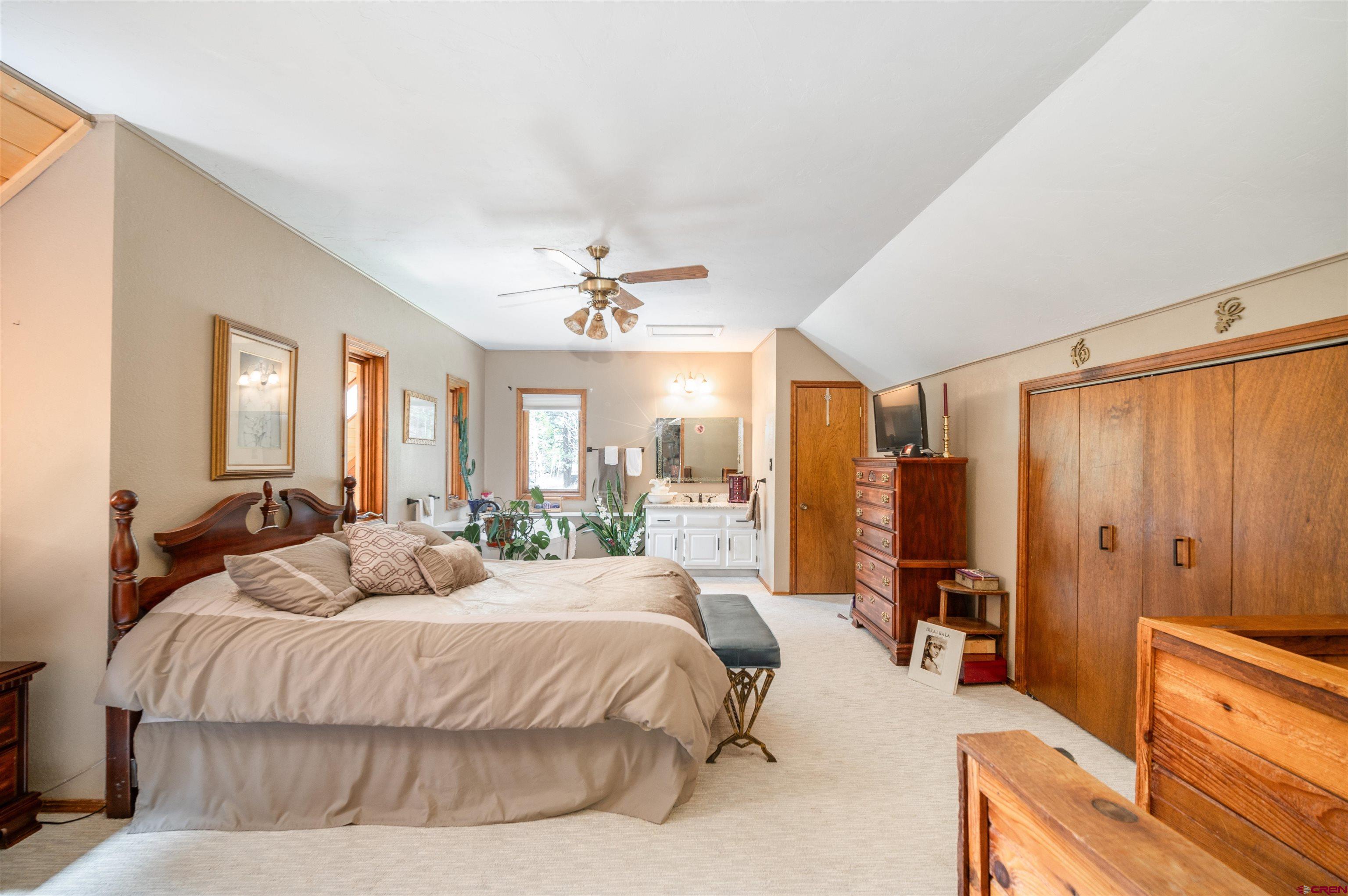 520 Los Ranchitos Drive Durango, CO 81301 - Photo 18 of 36 a spacious bedroom with a large bed a chandelier and dresser