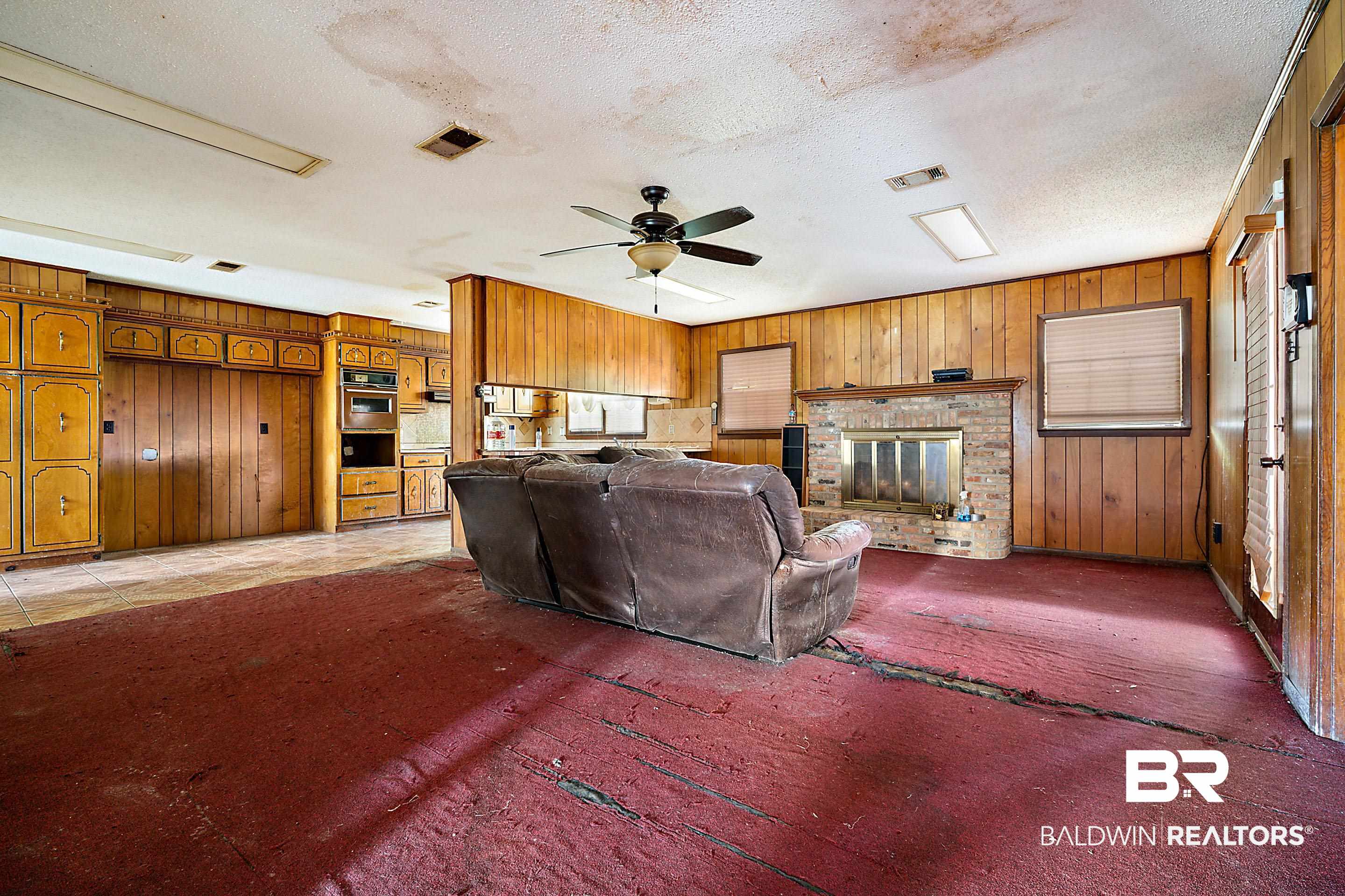 576 Markham Drive Mobile, AL 36609 - Photo 6 of 18 Living room with wooden walls, a textured ceiling, a ceiling fan, and a fireplace