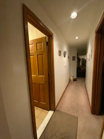a view of hallway with stainless steel appliances wooden floor and a cabinet