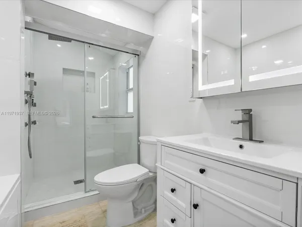 a bathroom with a sink a toilet and shower
