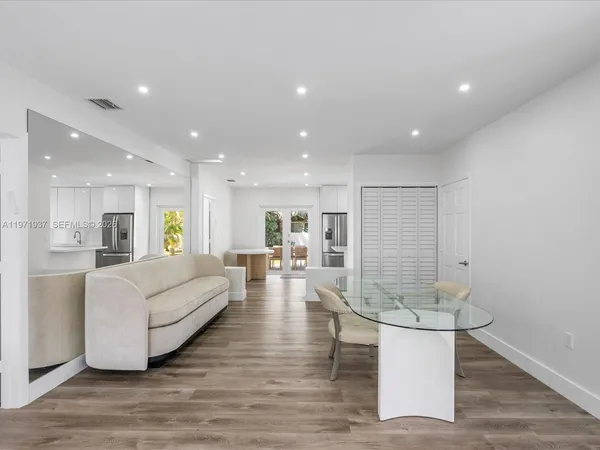 a living room with couches and kitchen view with wooden floor
