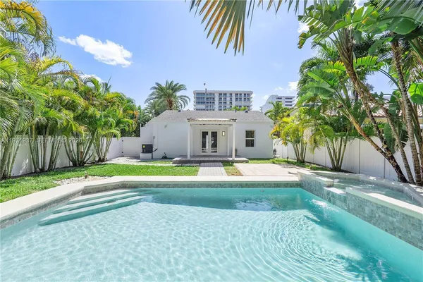 a view of a house with a yard and palm trees