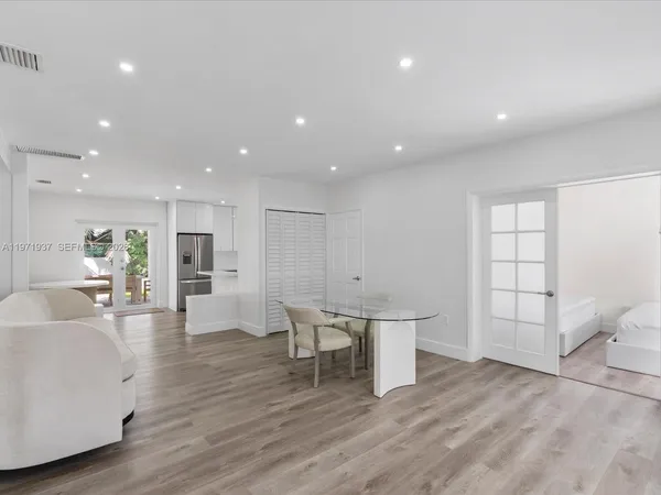 a large white kitchen with wooden floor and a toilet