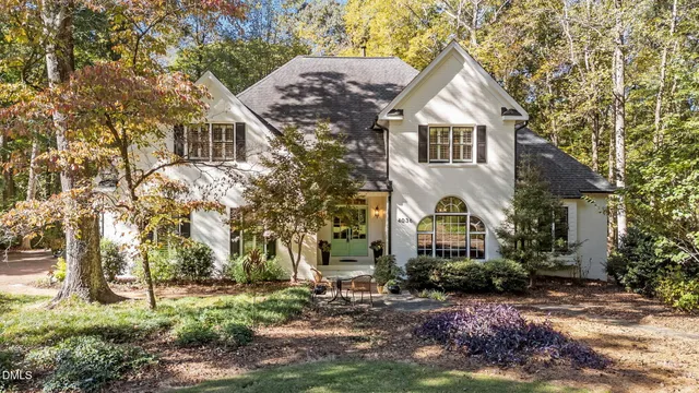 a view of a white house next to a yard with plants and trees