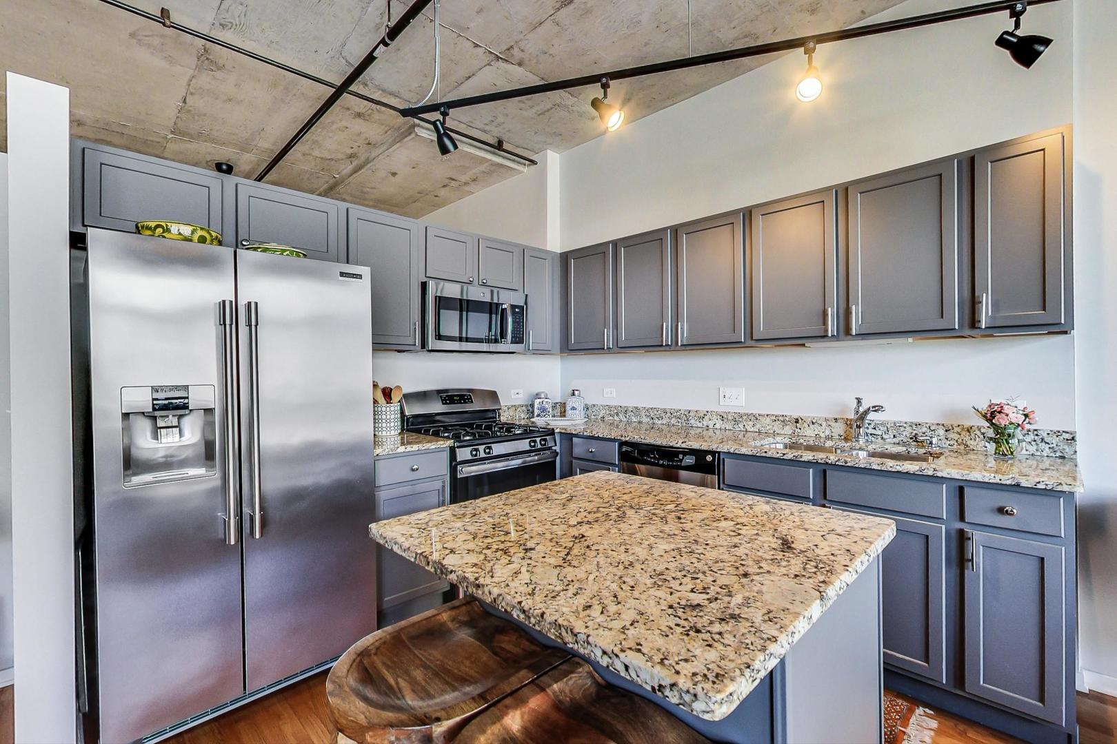 933 West Van Buren Street, Unit 726 Chicago, IL 60607 - Photo 11 of 31 a kitchen with granite countertop stainless steel appliances a refrigerator and a stove top oven