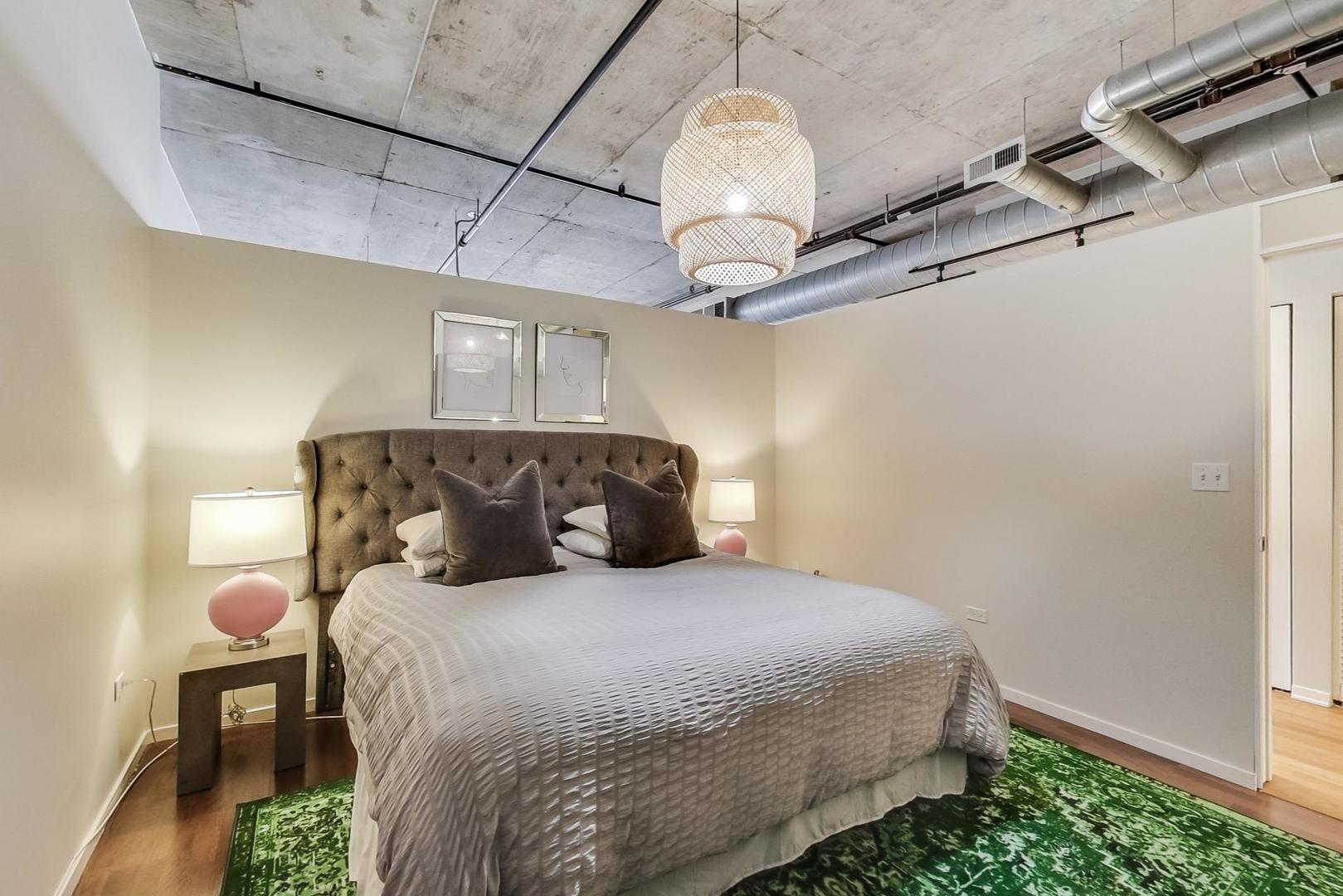 933 West Van Buren Street, Unit 726 Chicago, IL 60607 - Photo 14 of 31 a bedroom with a bed and chandelier