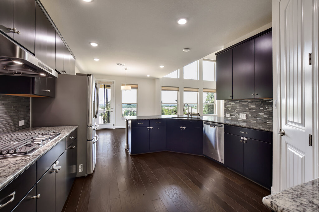 2521 Blended Tree Ranch Drive Leander, TX 78641 - Photo 11 of 40 a large kitchen with stainless steel appliances kitchen island granite countertop a large stove a sink dishwasher and wooden cabinets with wooden floor
