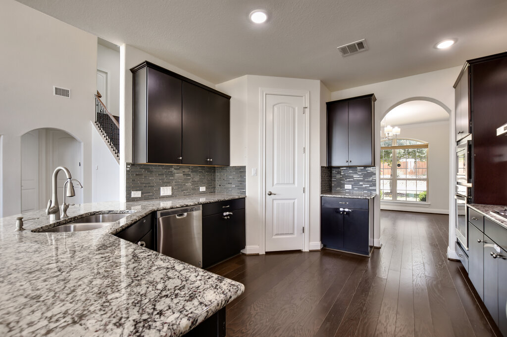 2521 Blended Tree Ranch Drive Leander, TX 78641 - Photo 13 of 40 a kitchen with stainless steel appliances granite countertop a sink dishwasher and a stove with wooden floor