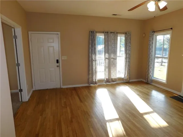 an empty room with wooden floor and windows