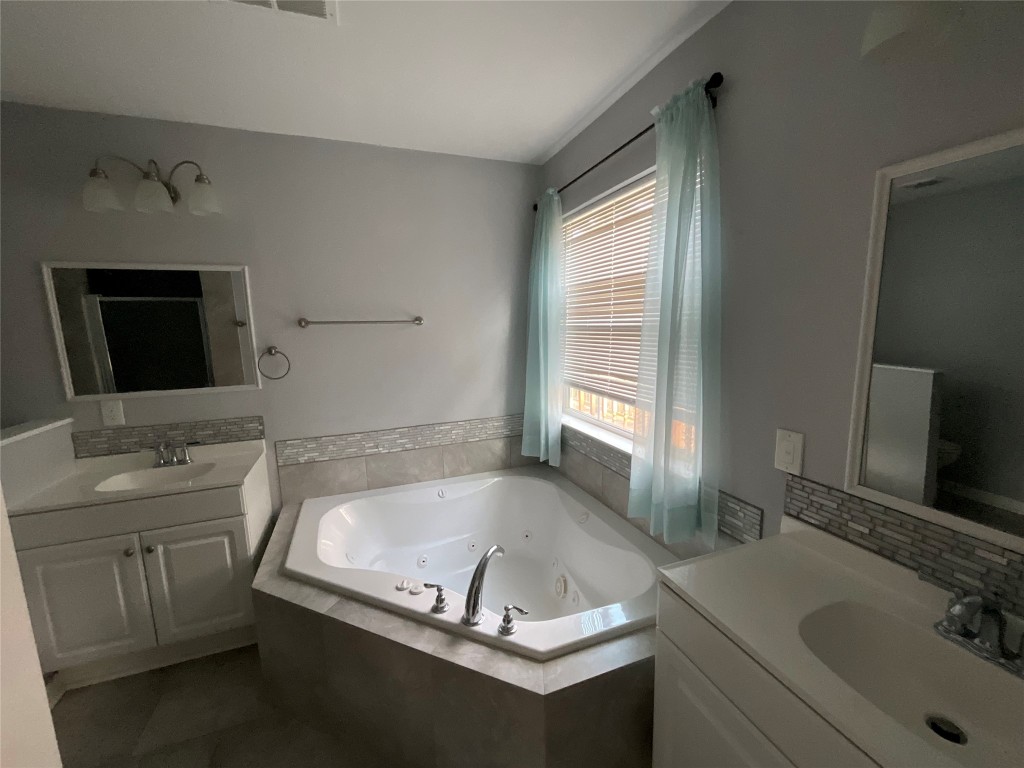 239 Old Firetower Road Bastrop, TX 78602 - Photo 30 of 39 a bathroom with a granite countertop sink a mirror and a bathtub