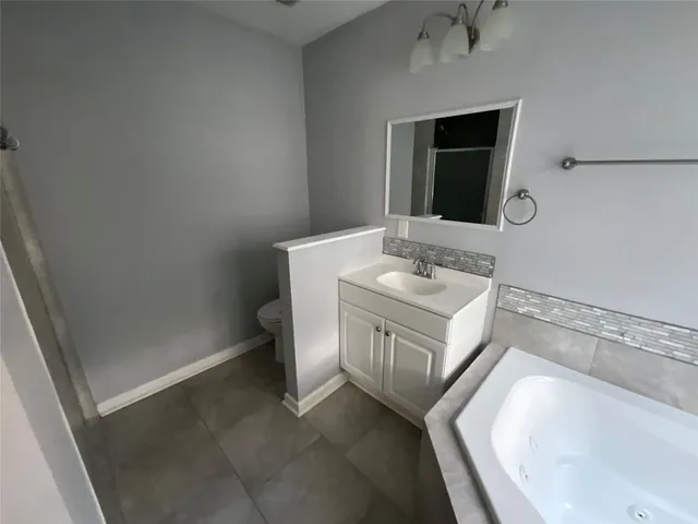 a bathroom with a granite countertop sink a mirror and a bathtub