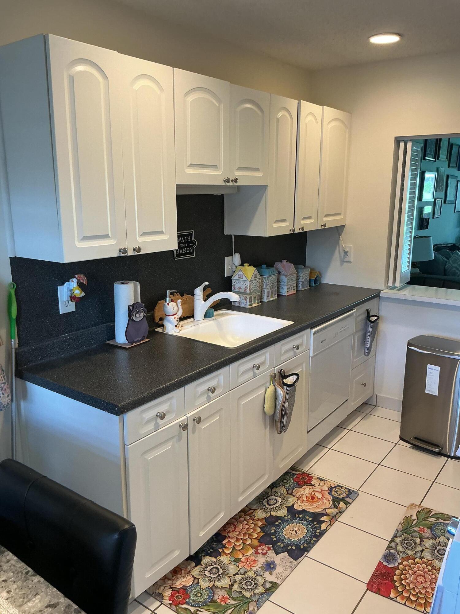 1580 Northwest 18th Avenue, Unit 98B Delray Beach, FL 33445 - Photo 3 of 16 a kitchen with granite countertop a sink a stove and cabinets