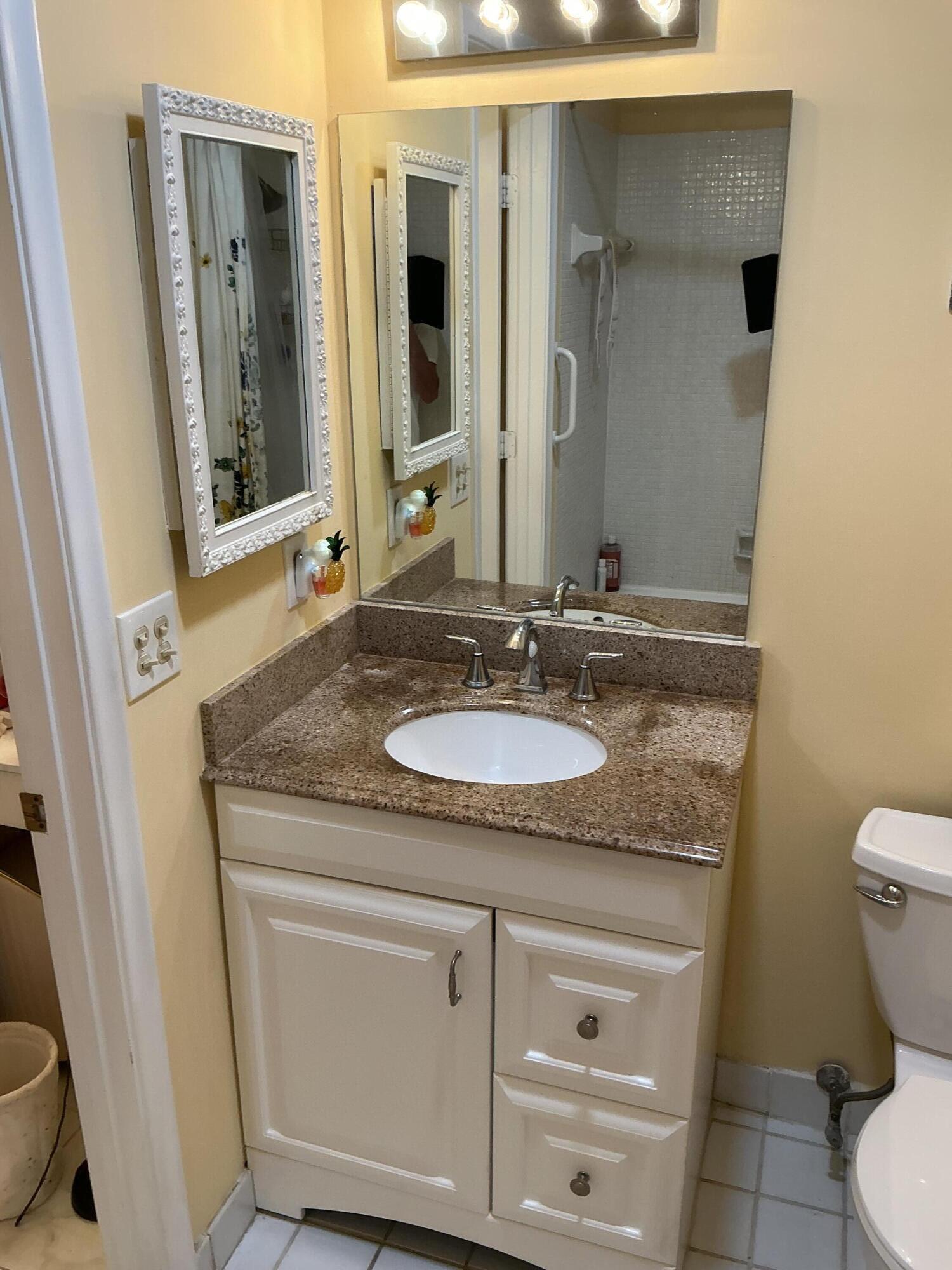 1580 Northwest 18th Avenue, Unit 98B Delray Beach, FL 33445 - Photo 10 of 16 a bathroom with a granite countertop sink and a mirror