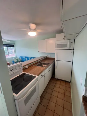 a kitchen with granite countertop a refrigerator a stove a sink and a refrigerator