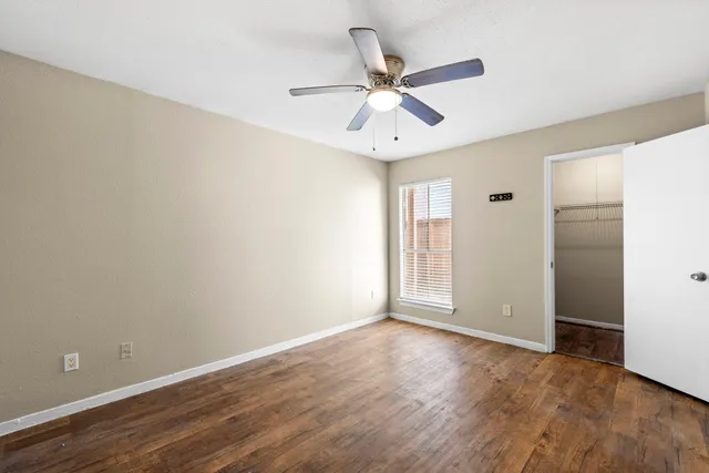 an empty room with a window and a ceiling fan