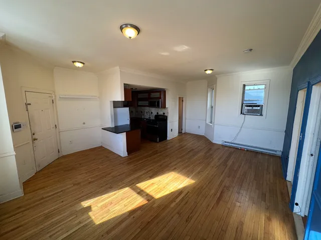 a view of a kitchen with wooden floor and a refrigerator