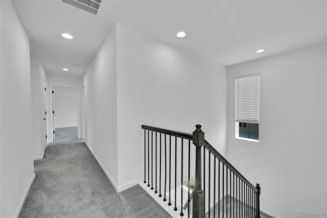 a view of an empty room with kitchen and wooden floor